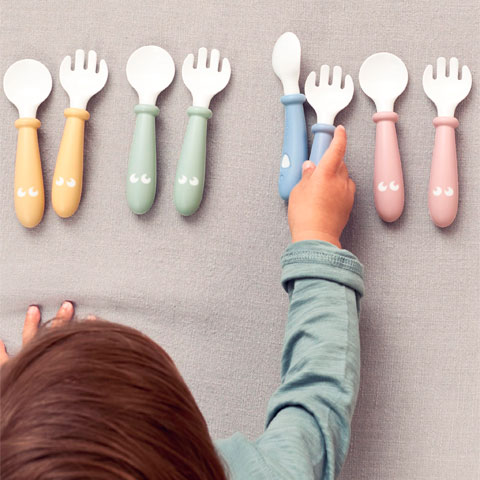 Niño pequeño cogiendo tenedores y cucharas de Babybjorn