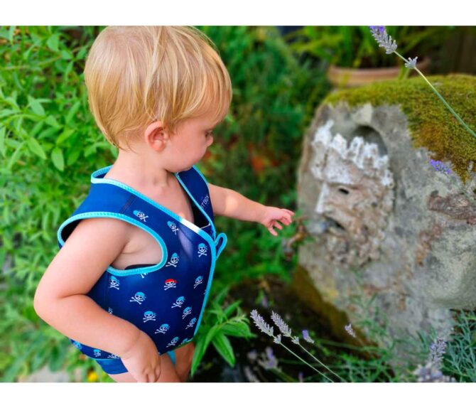 Niño pequeño en una fuente en el campo con el Chaleco flotador Btbox diseño estampado calaveras piratas