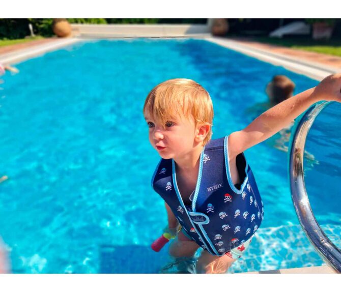 Niño pequeño en la piscina con Chaleco flotador Btbox diseño estampado calaveras piratas