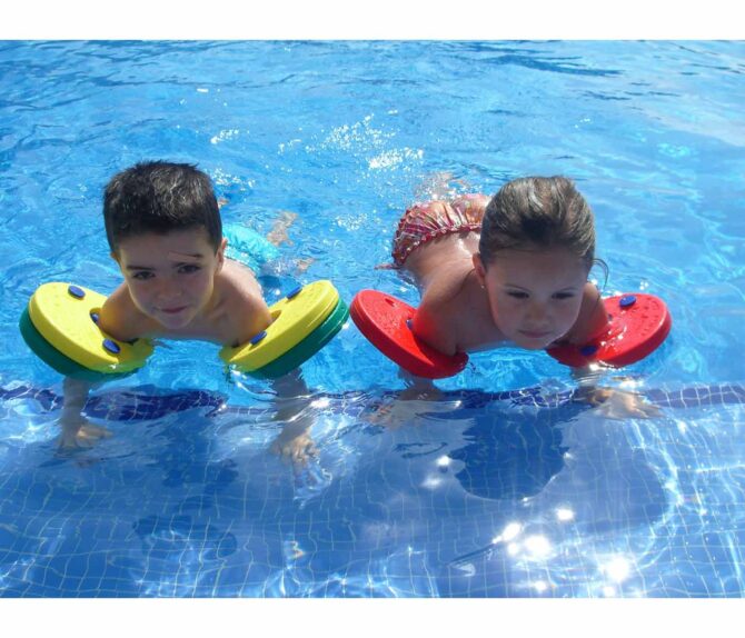 Un niño y una niña flotando en una piscina con los Manguitos flotador Delphin